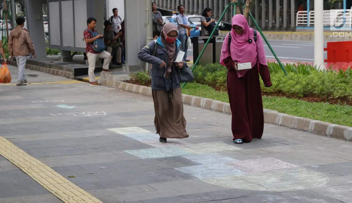 Warga mencoba permainan anak engkle di trotoar sekitar Halte Gelora Bung Karno, Jakarta, Jumat (17/5/2019). Koalisi Pejalan Kaki melakukan eksperimen permainan untuk mengedukasi kegiatan mengembalikan fungsi trotoar lebih dari sekedar ruang berjalan kaki. (Liputan6.com/Helmi Fithriansyah)