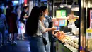 Dua wanita membeli makanan di pedagang kaki lima di Haikou, ibu kota Provinsi Hainan, China selatan (26/3/2020). Provinsi Kepulauan Hainan di China selatan pada Selasa (24/3) mencatatkan penurunan jumlah kasus penyakit coronavirus baru (COVID-19) yang ada menjadi nol. (Xinhua/Guo Cheng)