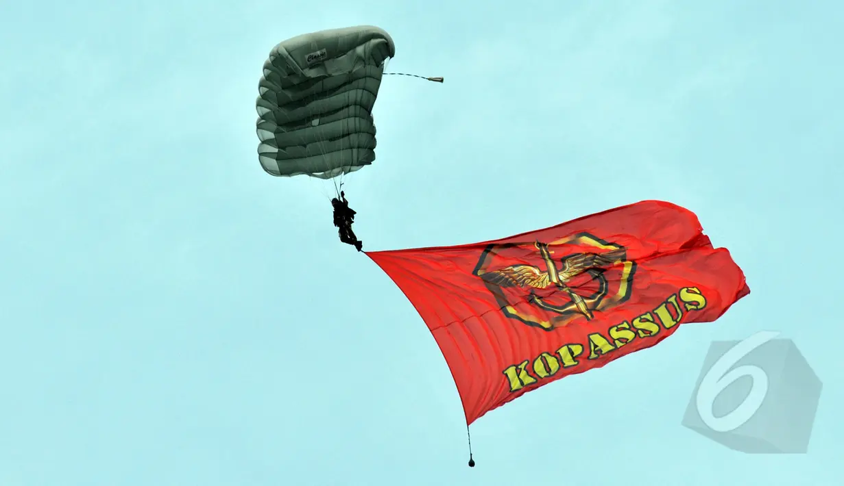 Seorang anggota membawa bendera Kopassus saat melakukan aksi terjun payung 18 lapis dalam perayaan HUT ke-63 satuan elite baret merah tersebut di Cijantung, Jakarta, Rabu (29/4/2015). (Liputan6.com/Herman Zakharia)