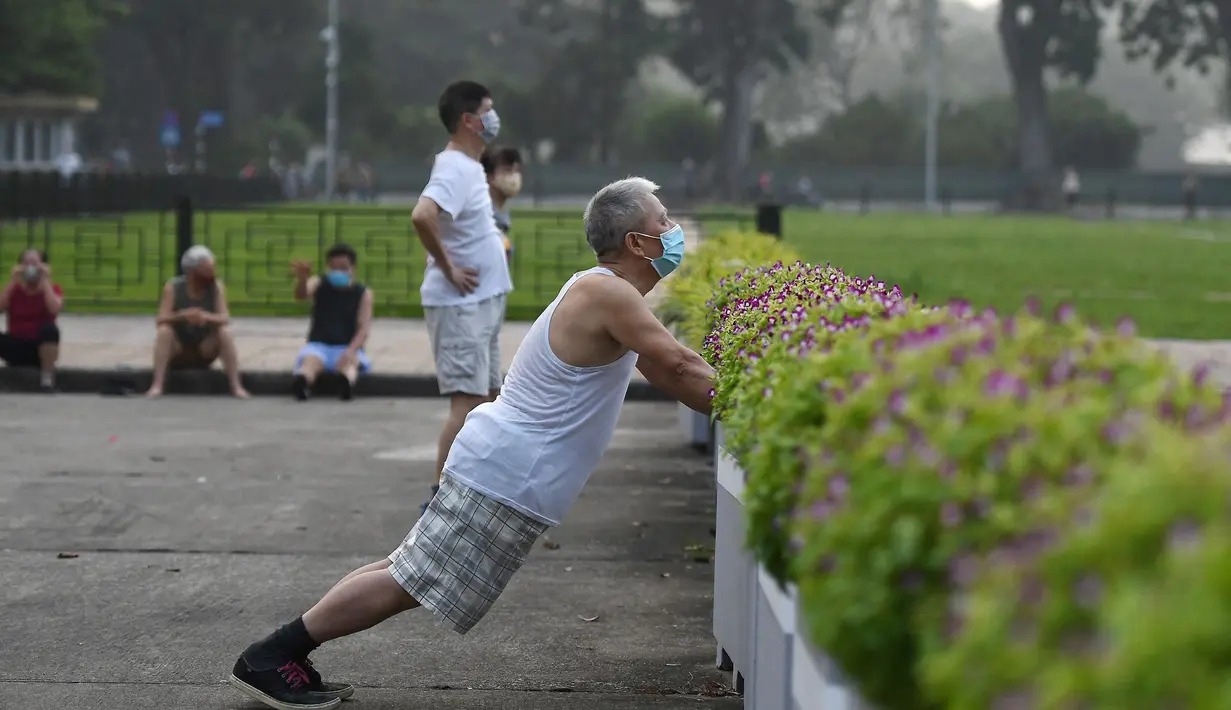 Seorang pria berolahraga di taman umum di Hanoi setelah kegiatan olahraga outdoor diizinkan menyusul pelonggaran pembatasan Covid-19, Selasa (28/9/2021). Sejauh ini, 94 persen dari populasi orang dewasa Hanoi yang berjumlah 5,75 juta telah menerima satu suntikan vaksin COVID-19. (Nhac NGUYEN/AFP)
