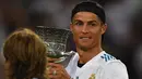 Senyum Cristiano Ronaldo saat memegang trofi Piala Super Spanyol 2017 di di Santiago Bernabeu stadium, Madrid, (16/8/2017). Real menang agregat 5-1. (AFP/Gabriel Bouys)