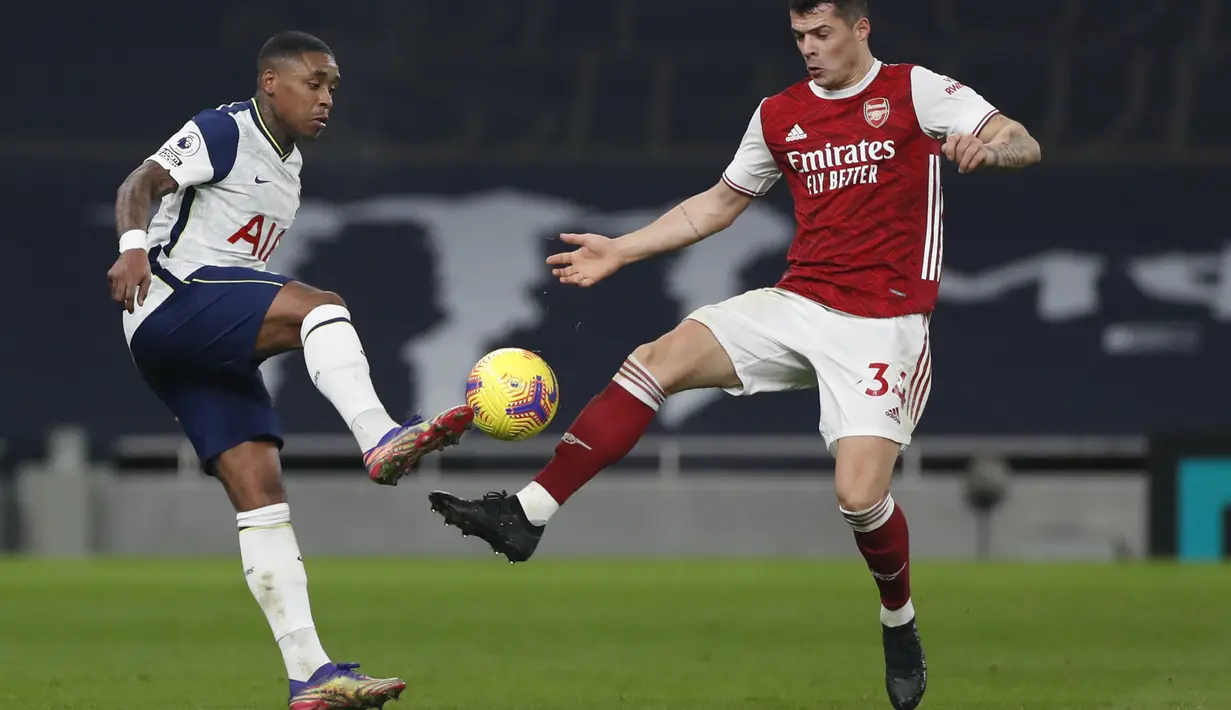 Penyerang Tottenham Hotspur, Steven Bergwijn berusaha melewati gelandang Arsenal, Granit Xhaka pada pertandingan lanjutan Liga Inggris di Tottenham Hotspur Stadium di London, Inggris , Minggu (7/12/2020). Tottenham menang 2-0. (Paul Childs/Pool via AP)