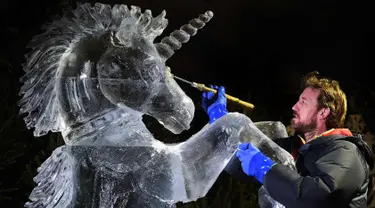 Pemahat es Darren Jackson memberi sentuhan akhir pada patung es Unicorn, sebelum melangsungkan pameran bertema "The Ice Adventure: A Journey Through Frozen Scotland" di Edinburgh, Skotlandia (14/11). (AFP Photo/Andy Buchanan)