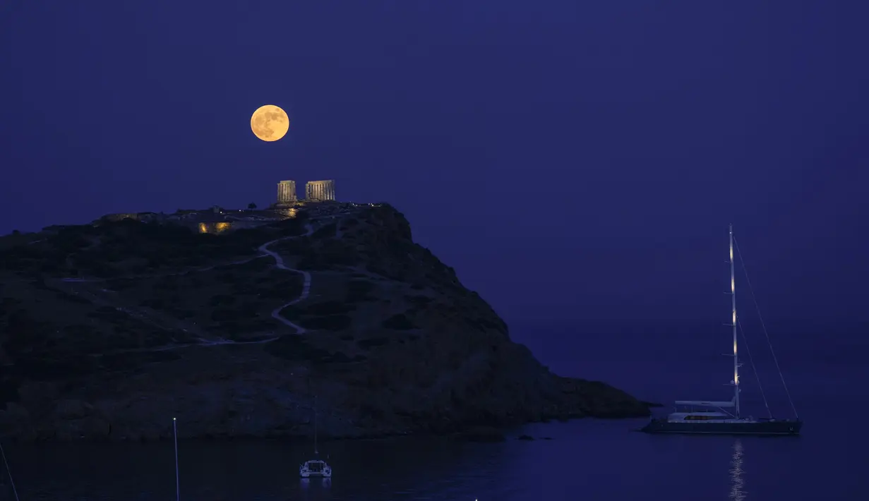 Bulan Purnama Stroberi atau Strawberry Full Moon muncul di belakang Kuil Poseidon marmer kuno di Cape Sounion, sekitar 70 Km selatan kota Athena, Yunani, Kamis (24/6/2021). Strawberry Full Moon adalah istilah yang diambil dari cerita tradisi dari suku-suku asli Amerika (AP Photo/Petros Giannakouris)