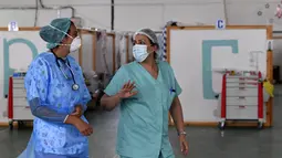 Petugas medis Tunisia yang merawat pasien di gym yang diubah untuk menangani lonjakan infeksi COVID-19 di pusat kota Kairouan pada 4 Juli 2021. Tunisia tengah berjuang menghadapi tsunami COVID-19 sementara jumlah orang yang meninggal akibat virus corona terus melonjak tinggi. (FETHI BELAID/AFP)