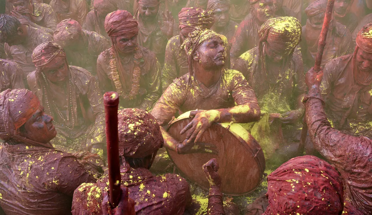 Sejumlah pria India bernyanyi dan bermain musik dengan tubuh berlumuran warna saat mengikuti festival Holi di desa Nandgaon di negara bagian Uttar Pradesh, India (7/3). (AFP)
