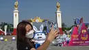 Bahkan, di tengah terik matahari seorang wanita menyempatkan berswafoto dengan maskot acara di luar Stadion Nasional Morodok Techo sesaat jelang upacara pembukaan Pesta Olahraga Asia Tenggara (SEA Games) ke-32 di Phnom Penh pada tanggal 5 Mei 2023. (NHAC NGUYEN/AFP)