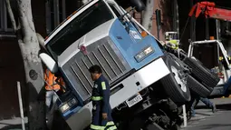 Kondisi truk yang terjebak di sebuah saluran pembuangan di San Francisco, AS, Jumat (5/5). Diduga karena muatan yang terlalu berat membuat bagian atas saluran pembuangan menjadi amblas. (AP Photo / Jeff Chiu)