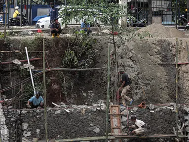 Pekerja menyelesaikan pengerjaan turap di bantaran Kali Kramat Jati, Jakarta, Jumat (20/1/2023). Pembangunan turap bertujuan untuk mencegah longsor yang dapat membahayakan warga sekitar. (Liputan6.com/Faizal Fanani)