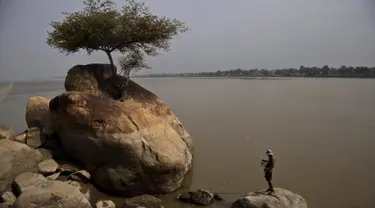 Seorang nelayan berdiri di atas batu dan menangkap ikan di sungai Brahmaputra di desa Kasoshila di pinggiran Gauhati, India (21/10/2019). Brahmaputra adalah salah satu sungai terbesar di Asia, yang melewati wilayah Tibet China, India, dan Bangladesh sebelum konvergen ke Teluk Benggala. (AP Photo/Anu