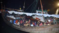 Pengungsi Rohingya duduk di perahu saat tiba di Pelabuhan Krueng Geukueh di Aceh Utara, Jumat pagi (31/12/2021). Kapal yang mengangkut sejumlah pengungsi itu ditemukan di 53 nautical mile dari Bireuen, Aceh. (AP Photo/Rahmat Mirza)