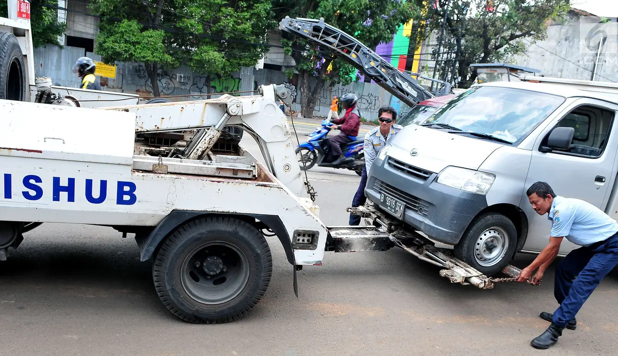 Petugas Dinas Perhubungan DKI Jakarta memasang alat derek untuk membawa mobil yang parkir di bahu jalan di kawasan Jatinegara, Jakarta, Senin (2/10). (Liputan6.com/Helmi Afandi)