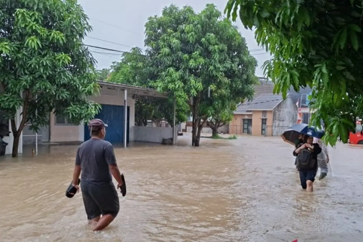 Warga melintas ditengah banjir di Kota Serang, Banten, Selasa (13/1/2026).