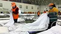 Para pekerja mengatur tempat tidur di pusat konvensi yang diubah menjadi rumah sakit sementara virus corona, Wuhan, Provinsi Hubei, China, Selasa (4/2/2020). Dari 427 korban tewas akibat virus corona, hampir seluruhnya terjadi di China. (Chinatopix via AP)