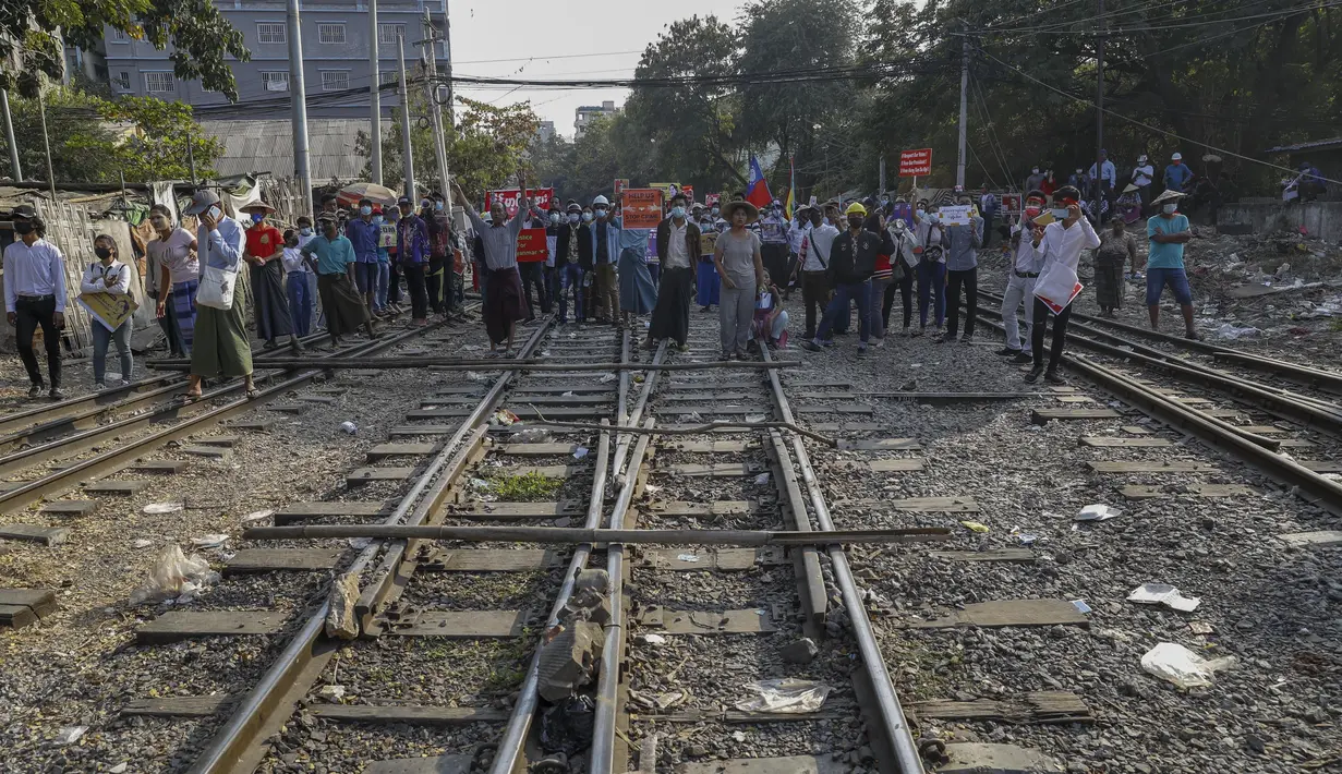 Demonstran berdiri di rel kereta api dalam upaya mengganggu layanan kereta selama protes terhadap kudeta militer di Mandalay, Myanmar (17/2/2021). Mereka berbondong-bondong memenuhi jalur kereta api di tengah terik matahari sambil mengangkat spanduk untuk mendukung gerakan pembangkangan. (AP Photo)