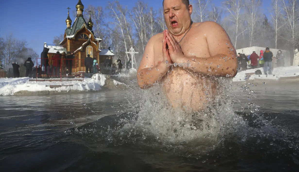 Seorang pria mandi di air selama perayaan Epiphany tradisional saat suhu turun menjadi sekitar -24 derajat di dekat biara Achairsky di luar kota Omsk di Siberia, Rusia (19/1/2021). Gereja Ortodoks Rusia mengikuti kalender Julian kuno, yang menurutnya Epiphany jatuh pada 19 Januari.  (AP Photo/Evgeni