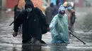 Orang-orang mengarungi jalan yang banjir setelah hujan lebat di Chennai, India (8/11/2021). Departemen Meteorologi India (IMD) memperkirakan lebih banyak curah hujan dalam beberapa hari mendatang. (AFP/Arun Sankar)