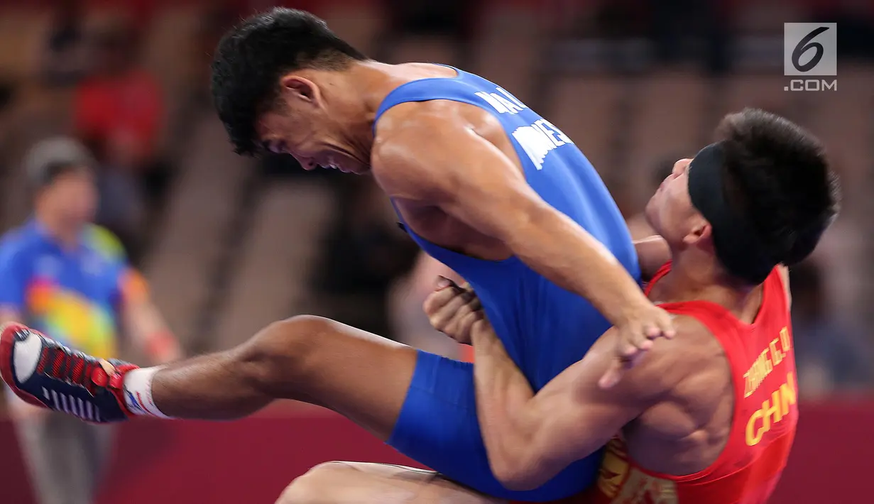 Pegulat China Zhang Gaoquan mengunci Muhammad Aliansyah dari Indonesia saat bertarung pada kelas putra 67 Kg Asian Games 2018 di arena gulat JCC Senayan, Selasa (21/8). Aliansyah kalah atas lawanya dengan skor 0-7. (Liputan6.com/Fery Pradolo)