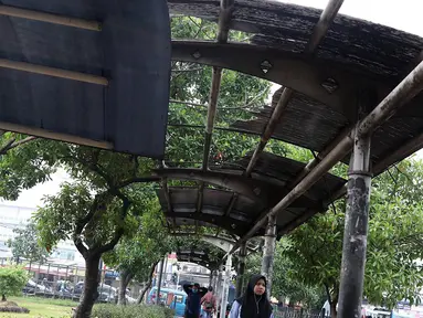 Warga melintasi jalur khusus pejalan kaki di kawasan Kampung Rambutan, Jakarta, Selasa (19/2). Atap rusak yang juga tidak dilengkapi dengan lampu penerangan mengganggu kenyamanan pejalan kaki. (Liputan6.com/Immanuel Antonius)