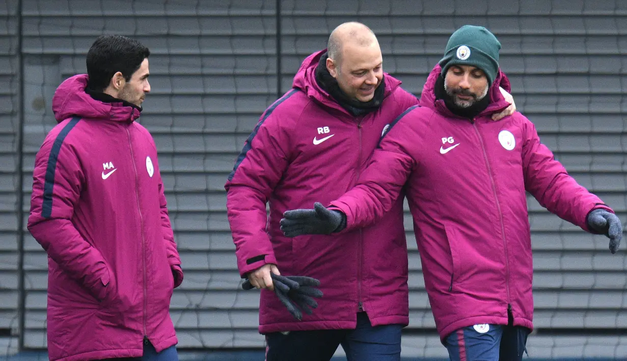Pelatih Manchester City, Pep Guardiola, bercanda dengan staf pelatih saat sesi latihan jelang laga Liga Champions di Manchester, Selasa (6/3/2018). Manchester City akan berhadapan dengan FC Basel. (AFP/ Oli Scarff)