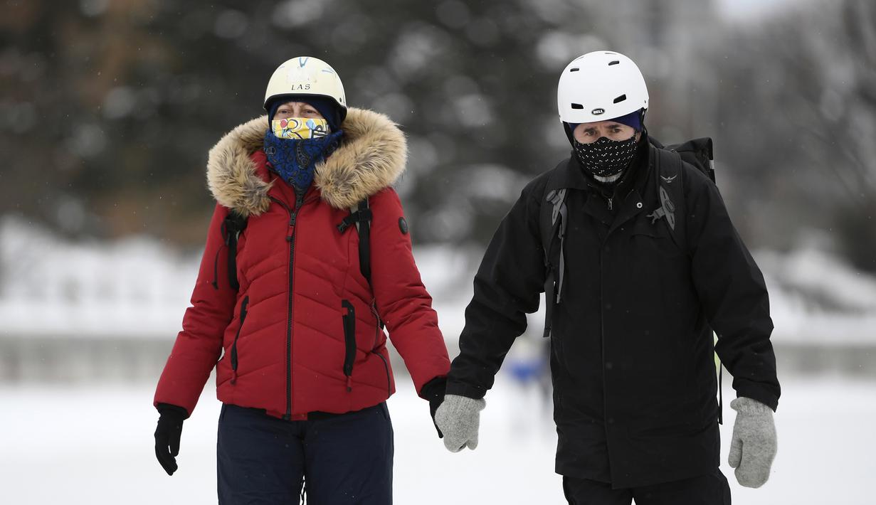 Orang-orang memakai masker berjalan di sepanjang Rideau Canal Skateway pada hari pembukaannya di tengah pandemi COVID-19 di Ottawa, Ontario, Kamis (28/1/2021). Rideau Canal Skateway dibuka Kamis pagi dengan sejumlah tindakan pencegahan COVID-19. (Justin Tang/The Canadian Press via AP)