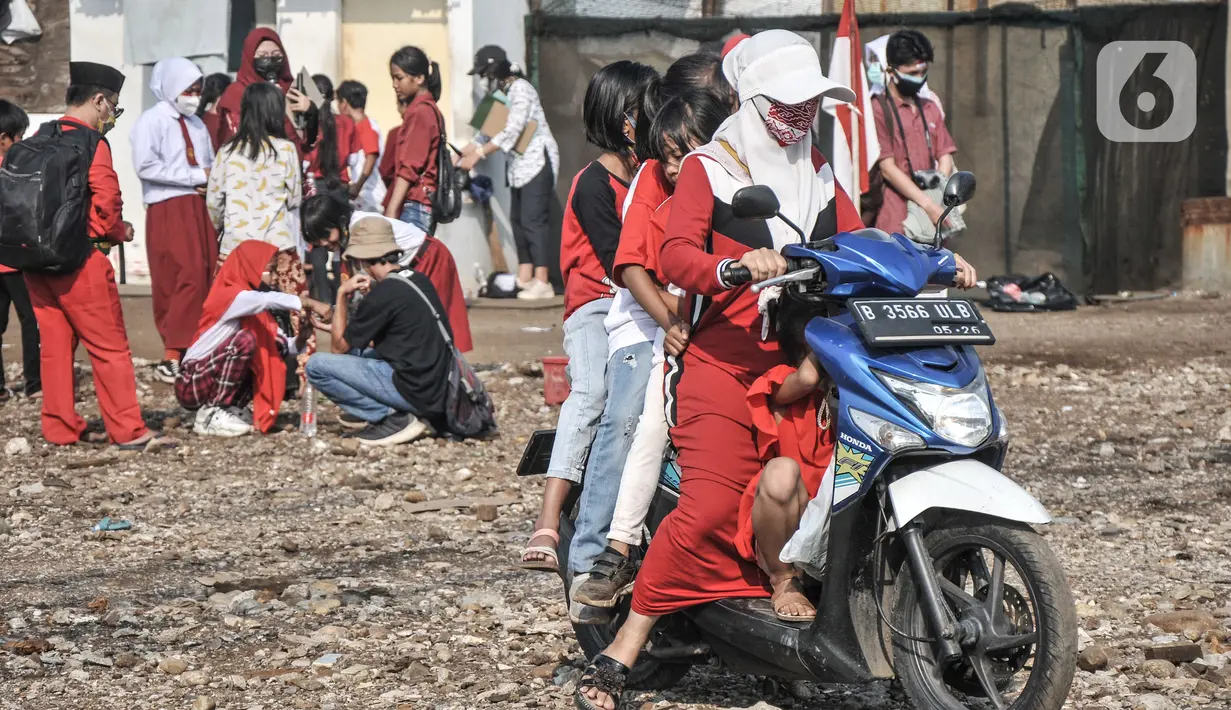 Warga memboncengi anaknya dengan sepeda motor saat akan mengikuti upacara Hari Kemerdekaan ke-76 RI di Cilincing, Jakarta, Selasa (17/8/2021). (merdeka.com/Iqbal S. Nugroho)