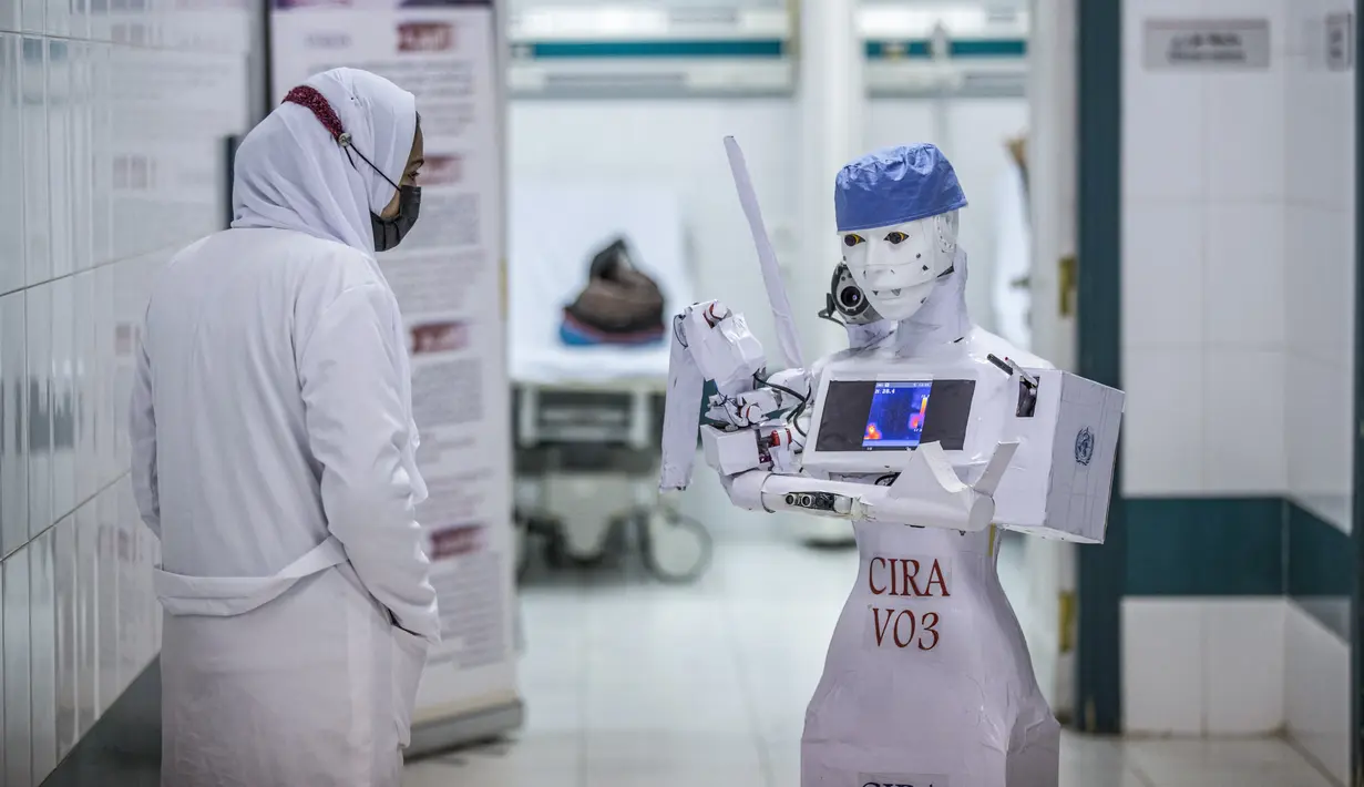 Perawat berdiri di dekat prototipe robot CIRA-03 untuk mengumpulkan sampel pengujian Swab Test COVID-19 di koridor rumah sakit swasta di kota Tanta, Mesir pada 20 Maret 2021. Prototipe robot itu bagian dari proyek mandiri untuk membantu dokter dalam meredam pandemi COVID-19. (Khaled DESOUKI/AFP)