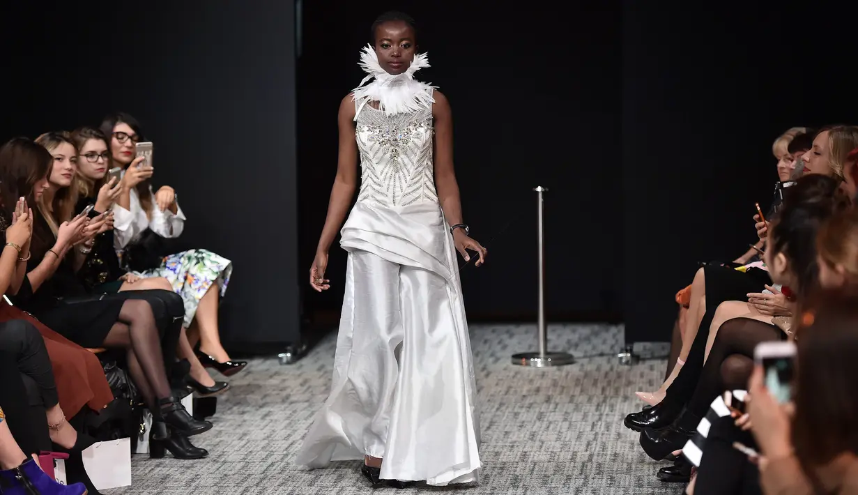 Model tunanetra mengenakan busana label US, American Wardrobe, sambil berpegangan pada tali ketika berjalan di atas catwalk pagelaran Paris Fashion Week di Paris, Rabu (5/10). (AFP PHOTO/Christophe Archambault)