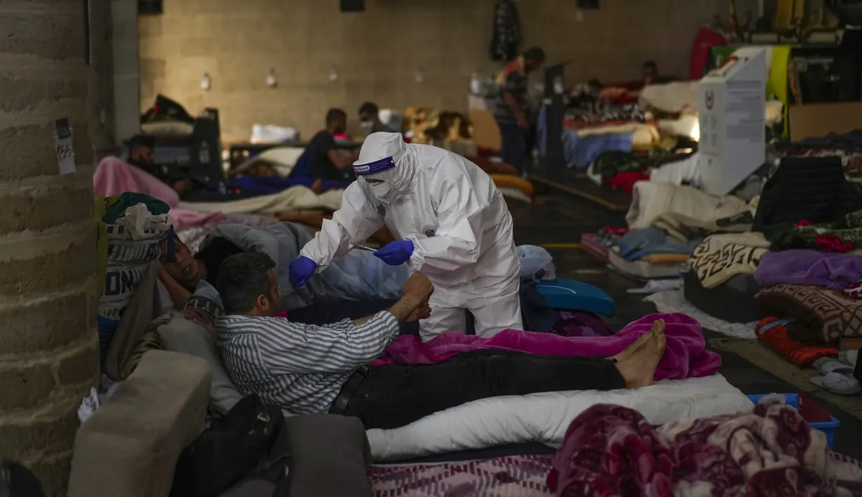 Petugas kesehatan Palang Merah memerika seorang pria yang mogok makan saat menempati gereja Saint-Jean-Baptiste-au-Beguinage di Brussel, Senin (7/6/2021). Puluhan migran tanpa surat resmi tersebut mogok makan untuk menarik perhatian otoritas Brussel atas penderitaan mereka. (AP Photo/Francisco Seco)
