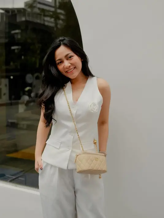 Potret ayu Rachel Vennya pakai atasan vest putih dipadunya dengan celana panjang yang juga berwarna putih dan mini sling bag bernuansa nude. [Foto: Instagram/rachelvennya]