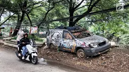 Pengendara motor melintas disamping sebuah mobil patroli Polsek Tanah Abang, Jakarta, Rabu (6/3). Mobil operasional merk KIA berkarat dan tidak tertutup terpal. (Liputan6.com/Fery Pradolo)