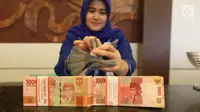 Petugas menunjukkan uang kertas rupiah di Bank BUMN, Jakarta, Selasa (17/4). Rupiah siang ini melemah dibandingkan tadi pukul 09.00 WIB di level Rp 13.771 per dolar AS. (Liputan6.com/Angga Yuniar)