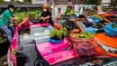 Karyawan menanam sayuran di atap taksi-taksi yang terbengkalai di pool taksi di Bangkok, Thailand, Rabu (15/9/2021). Para pekerja pertunjukan, dan pengemudi taksi termasuk di antara yang paling terpukul oleh kehilangan pekerjaan selama pandemi virus corona COivd-19. (Jack TAYLOR/AFP)