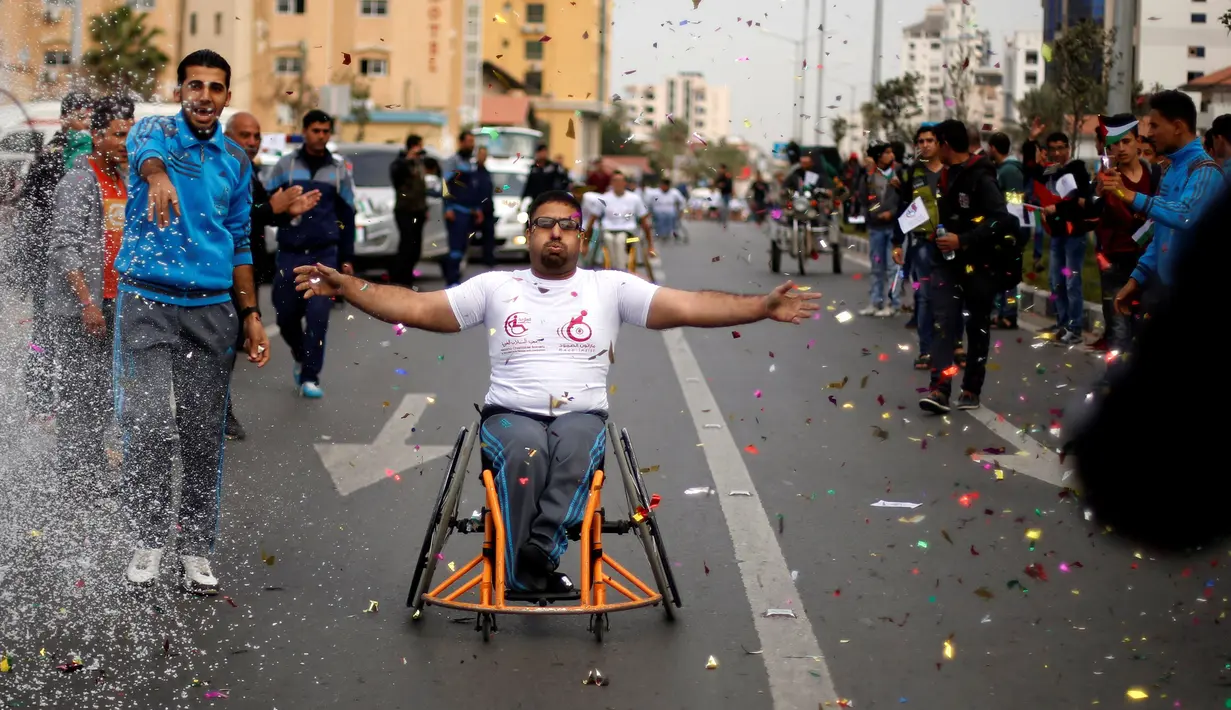 Peserta melakukan selebrasi usai mencapai garis finis dalam perlombaan kursi roda di Kota Gaza, (29/11). Lomba ini diselenggarakan untuk para warga yang mengalami cacat fisik akibat konflik sejak tahun 2008 dengan militer Israel. (REUTERS/Suhaib Salem)