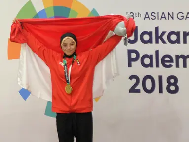 Pesilat Indonesia Sarah Tria Monita mengangkat bendera Merah Putih usai menaklukkan Nong Oy Vongphakdy asal Laos dalam babak final Kelas C Putri Asian Games 2018 di Jakarta, Senin (27/8). Sarah menang dan mendapatkan medali emas. (Merdeka.com/Arie Basuki)