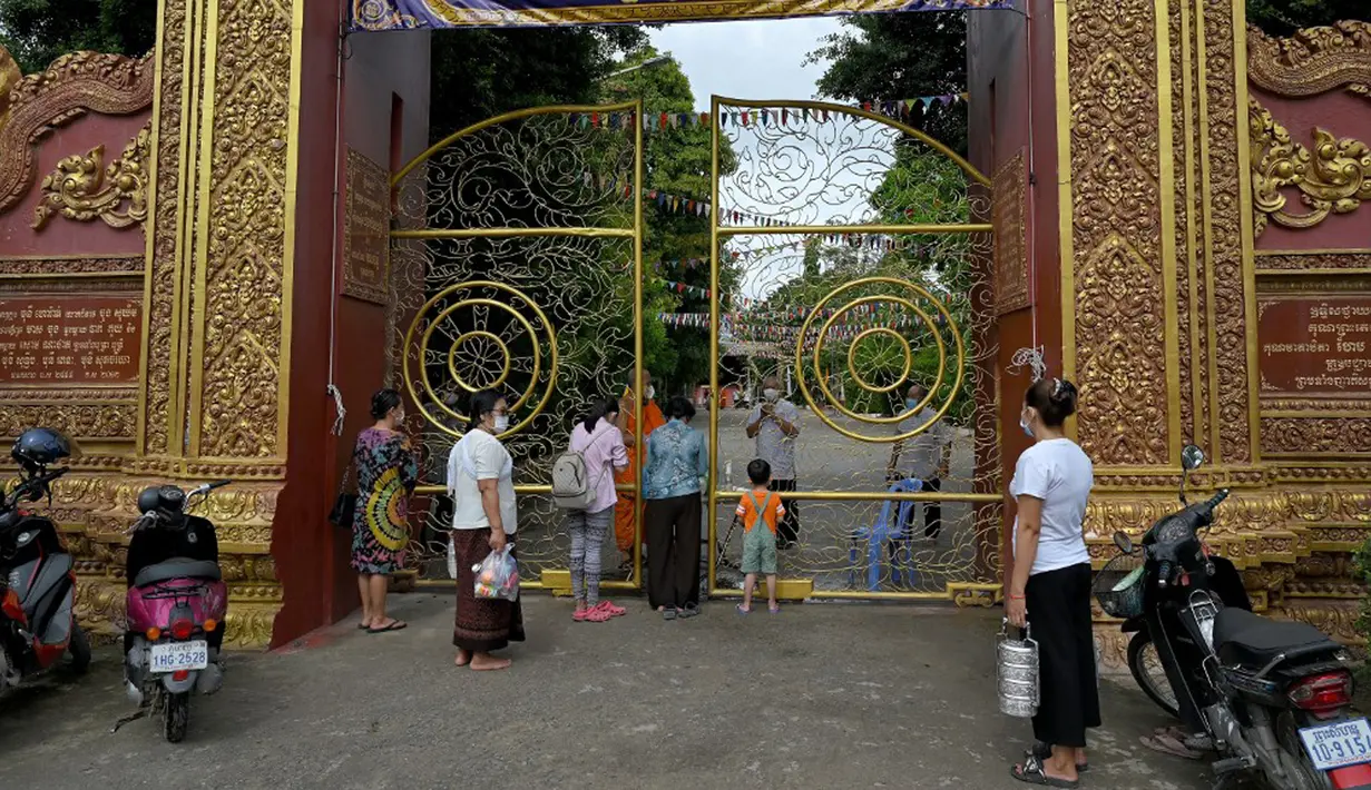 Warga antre untuk memberikan makanan dan sedekah kepada biksu Buddha saat Festival Pchum Ben (Festival Kematian) di luar pagoda di Phnom Penh, Kamboja, 24 September 2021. Pihak berwenang menghentikan perayaan Festival Kematian karena pandemi COVID-19. (TANG CHHIN Sothy/AFP)