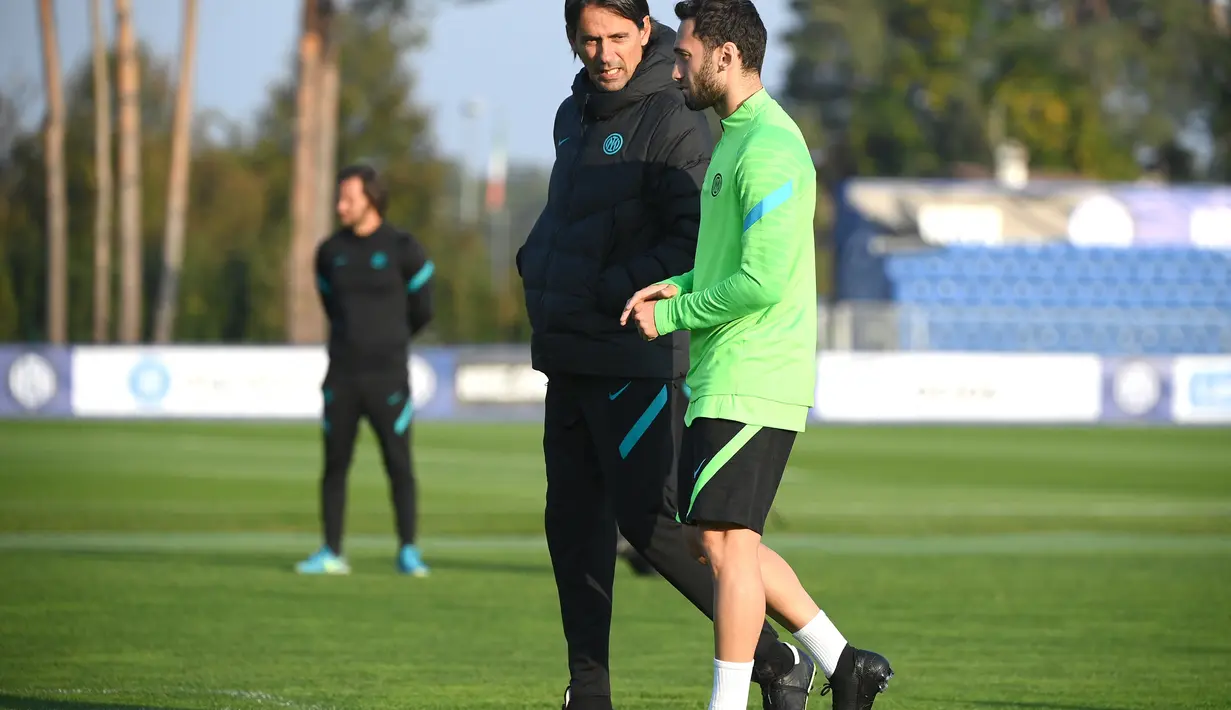 Gelandang Inter Milan, Hakan Calhanoglu berbincang dengan Pelatih Simone Inzaghi selama sesi latihan tim di Suning Training Center di Appiano Gentile dekat Milan(18/10/2021). Inter Milan akan bertanding melawan Sheriff pada Grup D Liga Champions. (AFP/Marco Bertorello)