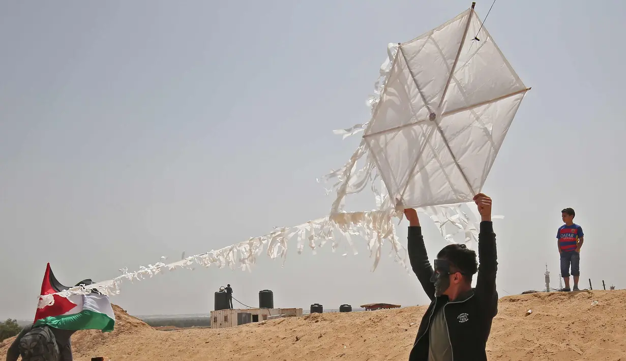 Warga Palestina bersiap menerbangkan layang-layang yang telah diberikan bom molotov di atas pagar perbatasan dengan Israel, di pinggiran timur Kota Gaza (20/4). Unjuk rasa warga Palestina terhadap Isrel memasuki minggu keempat. (AFP Photo/Mohammed Abed)