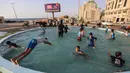 Anak-anak Palestina bermain di air mancur umum selama hari musim panas di Kota Gaza (20/7/2020). Musim panas yang terjadi di Palestina membuat anak-anak memenuhi air mancur. Mereka berupaya mendinginkan tubuh mereka dengan cara berenang di air mancur tersebut. (AFP Photo/Mahmud Hams)