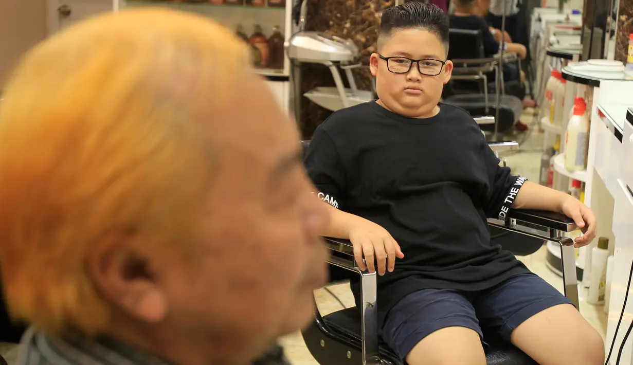 Le Phuc Hai, 66 tahun (kiri) dan To Gia Huy , 9 tahun, setelah rambut mereka dipangkas dengan gaya pemimpin Korea Utara Kim Jong-un dan Presiden Amerika Serikat, Donald Trump di sebuah salon di Hanoi, Vietnam, 19 Februari 2019. (AP/Hau Dinh)