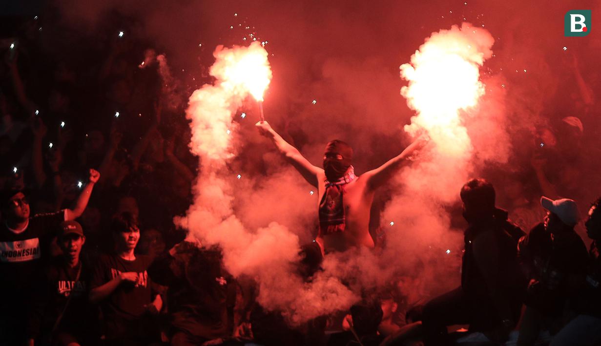 <p>Suporter Timnas Indonesia U-19 menyalakan suar saat laga Grup A Piala AFF U-19 2022 antara Timnas Indonesia U-19 melawan Timnas Vietnam U-19 di Stadion Patriot Candrabhaga, Bekasi, Jawa Barat, Sabtu (02/07/2022). (Bola.com/Ikhwan Yanuar)</p>