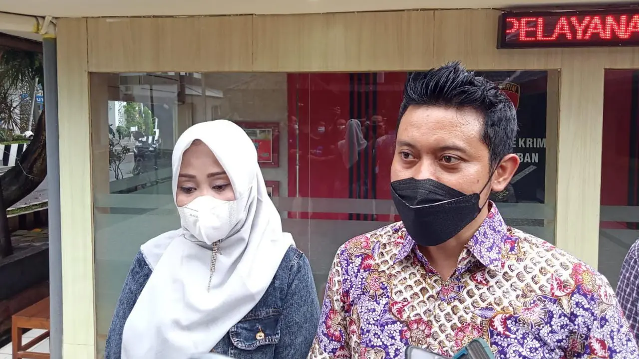 Wellem Mintarja kuasa hukum korban sambil menunjukkan bukti laporannya di Mapolres Tuban. (Adirin/Liputan6.com)