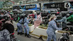 Sejumlah perserta yang tergabung dalam Forum Kader Bela Negara DKI Jakarta membagikan bunga dan masker kepada pengguna jalan di Jalan Thamrin, Jakarta, Rabu (22/12/2021). Aksi tersebut merupakan bentuk apresiasi terhadap kaum perempuan terutama pada peringatan Hari Ibu. (Liputan6.com/Faizal Fanani)