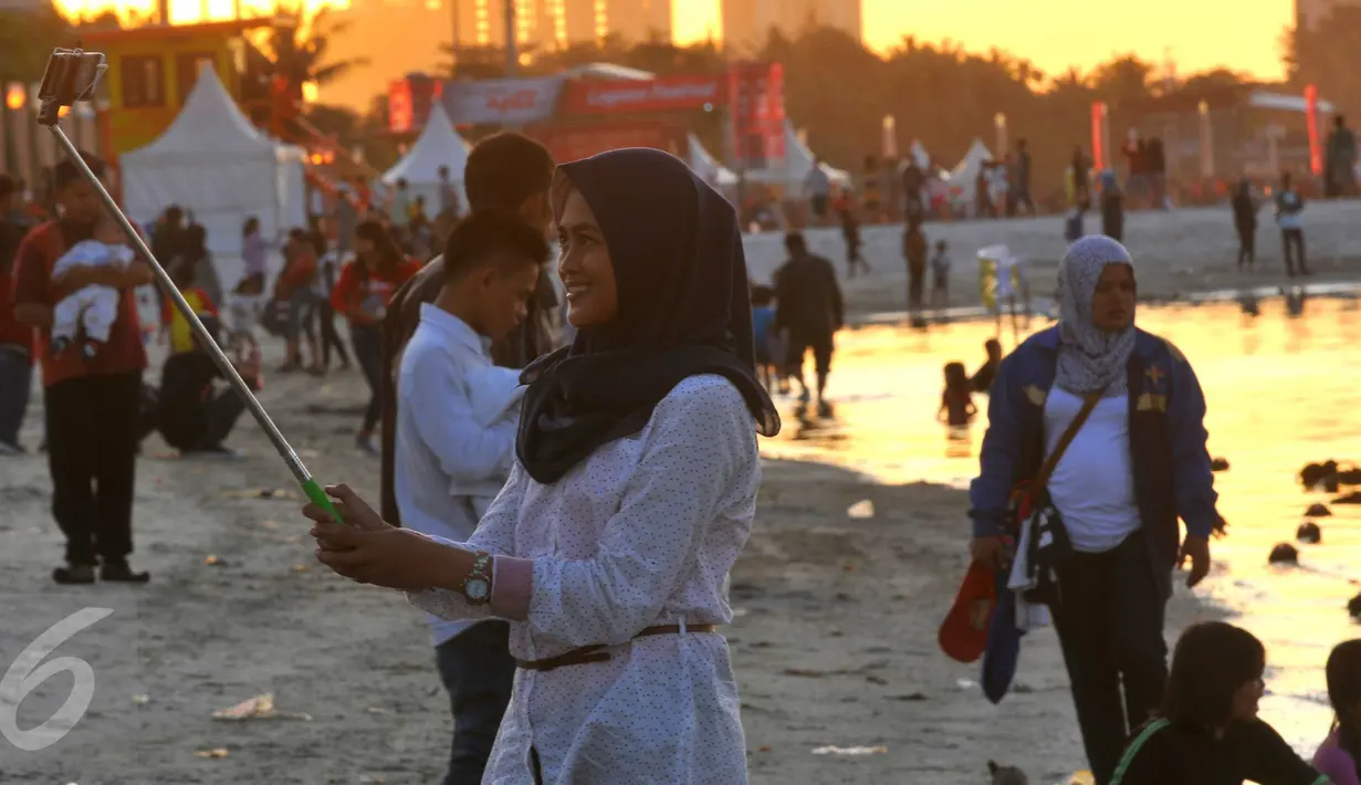 Pengunjung berselfie sambil menimmati pemandangan di pantai Ancol, Jakarta, (31/12). Pemprov DKI Jakarta menyarankan untuk warga Jakarta yang ingin merayakan malam pergantian tahun di pusatkan di Pantai Ancol. (Liputan6.com/Gempur M Surya)
