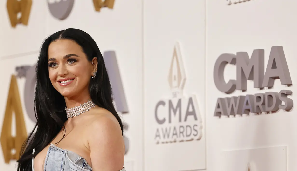 Katy Perry berpose sambil tersenyum saat menghadiri The 56th Annual CMA Awards di Bridgestone Arena di Nashville, Tennessee pada 9 November 2022. Ia melengkapi penampilannya dengan kalung mutiara chunky. (Jason Kempin/Getty Images/AFP)
