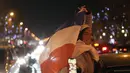 Suporter membawa bendera Prancis di jalan Champs Elysees usai kemenangan pertandingan semifinal Piala Dunia 2022 melawan Maroko, di Paris, Kamis (15/12/2022). Prancis berhasil mengalahkan Maroko dengan skor 2-0 dan melaju ke babak final menghadapi Argentina. (AP Photo/Thibault Camus)