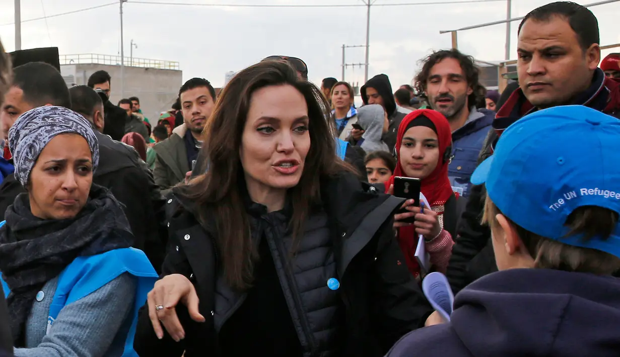 <p>Utusan khusus lembaga pengungsi PBB, aktris Angelina Jolie menyapa warga saat mengunjungi Kamp Pengungsi Suriah Zaatari di Mafraq, Yordania, Minggu (28/1). Jolie turut mengajak dua buah hatinya, Zahara (13) dan Shiloh (11). (Khalil MAZRAAWI/AFP)</p>