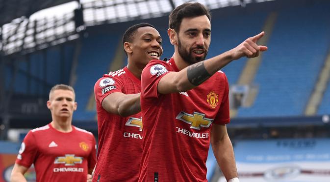 Gelandang Manchester United, Bruno Fernandes (depan) melakukan selebrasi usai mencetak gol pertama timnya ke gawang Manchester City melalui eksekusi penalti dalam laga lanjutan Liga Inggris 2020/21 di Etihad Stadium, Minggu (7/3/2021). MU menang 2-0 atas Mancity. (AFP/Laurence Griffiths/Pool)