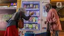 Calon penumpang kereta melakukan transaksi pembelian melalui vending machine BUMN untuk UMKM di Stasiun Gondangdia, Jakarta, Senin (22/1/2024). (Liputan6.com/Angga Yuniar)