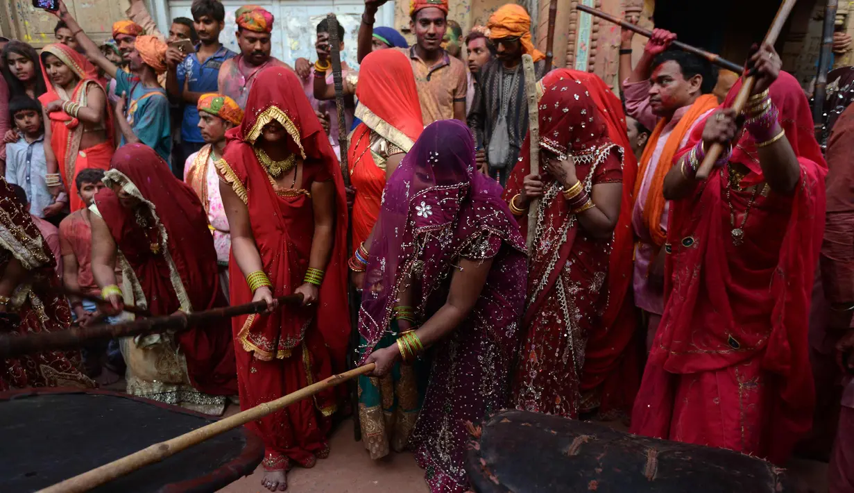 Sejumlah wanita memukul pria dengan tongkat (lathi) selama perayaan Lathmar Holi di Barsana di Mathura, India, (24/2). Lathmar Holi adalah perayaan lokal festival Hindu Holi, biasanya beberapa hari sebelum festival Holi. (AFP Photo/Dominique Faget)